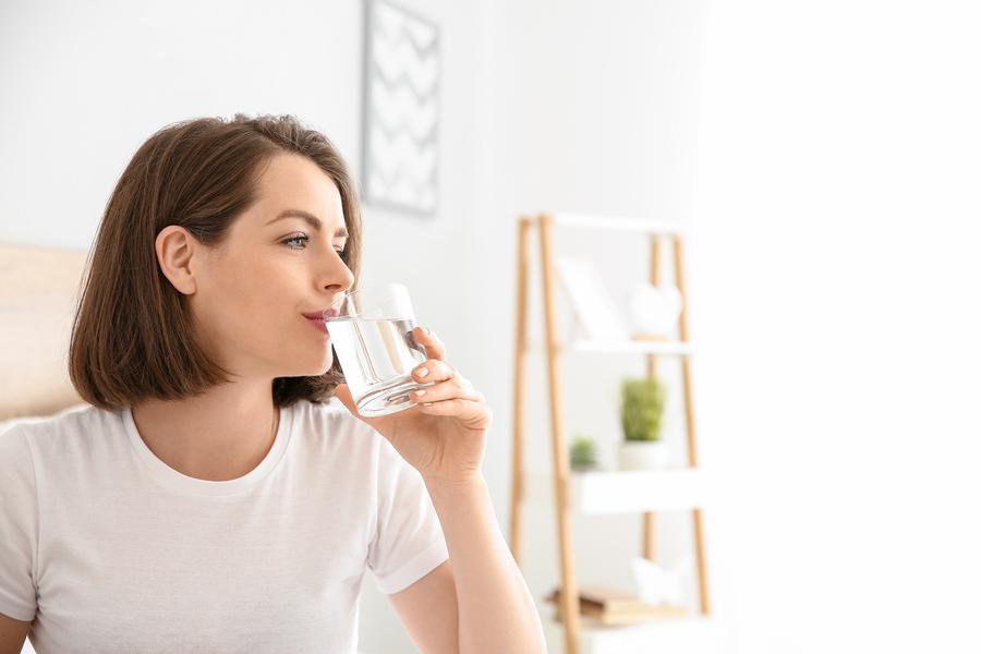 young woman drinking chlorine free filtered drinking water in a glass